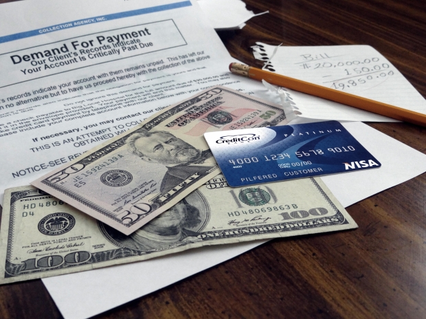 Photograph of a pile of bills, cash, and a credit card